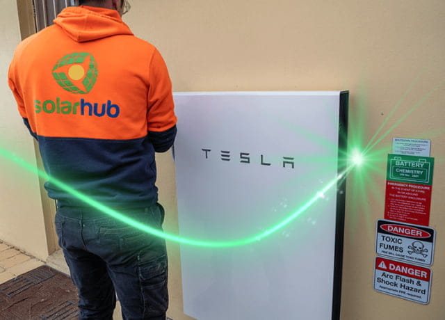 SolarHub technician installing a Tesla home battery