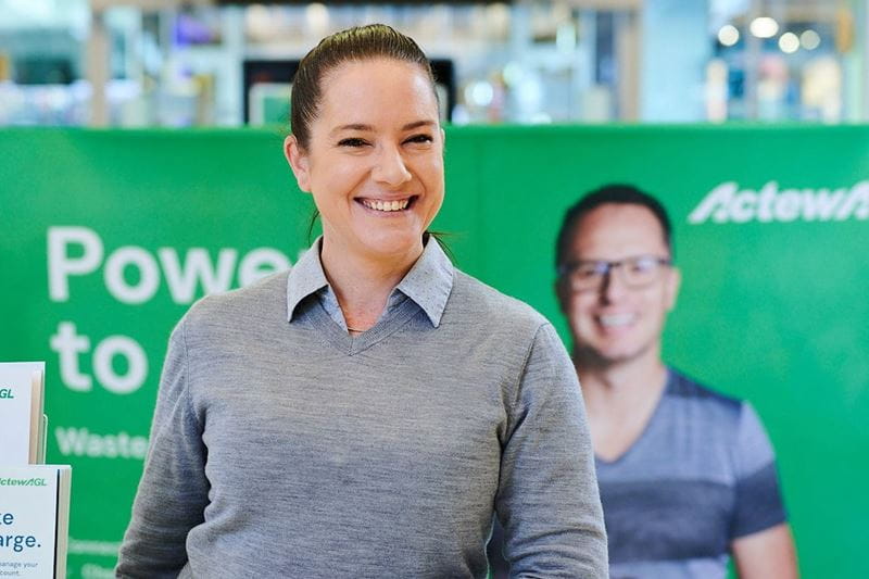 ActewAGL team member smiling with a banner in the background