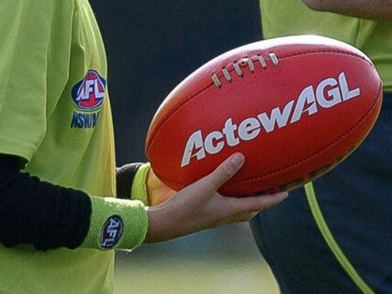 ActewAGL branded football being help by someone in an AFL shirt