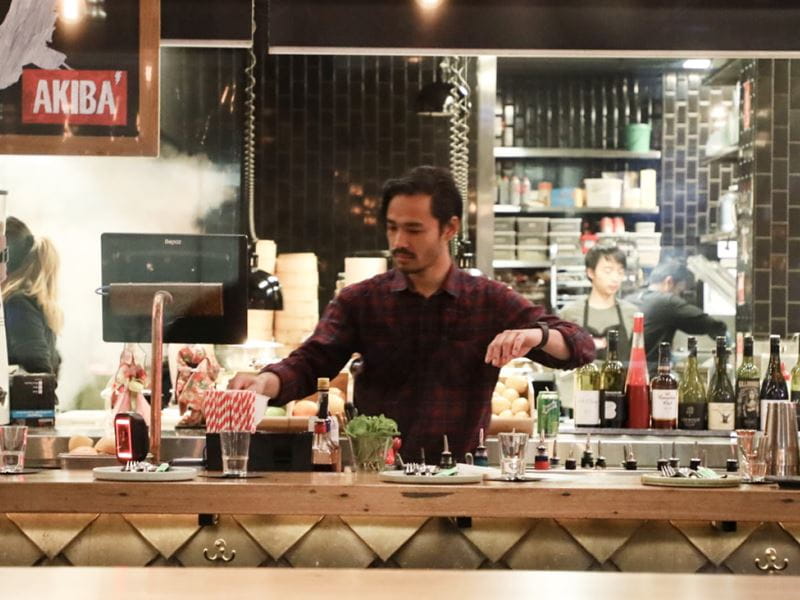 A man in a collared shirt working at a bar mixing drinks