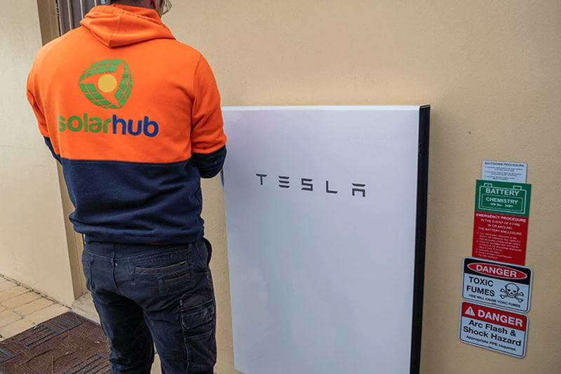 A man standing next to a Tesla charging station