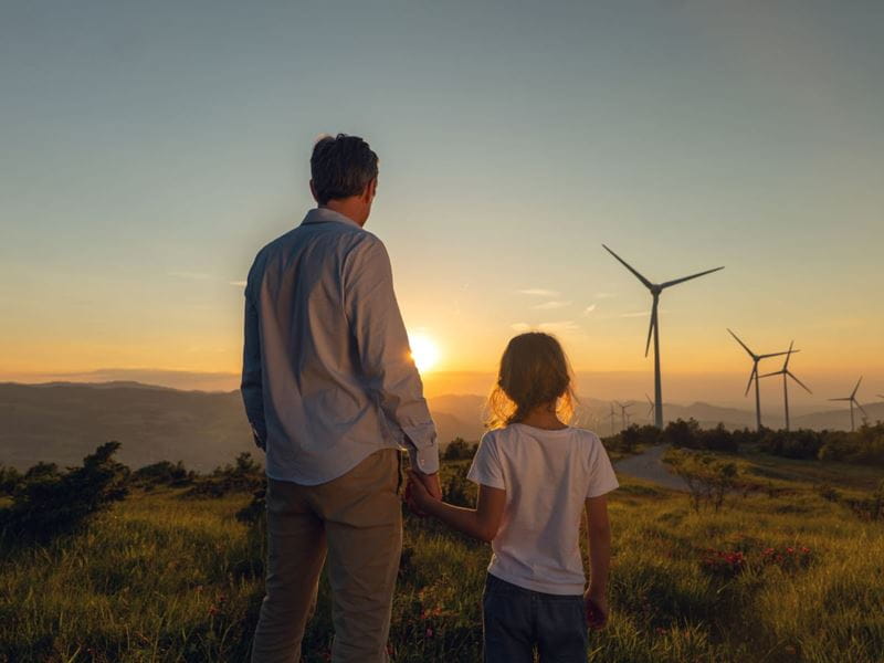A man and a girl looking at solar windmill during sunset