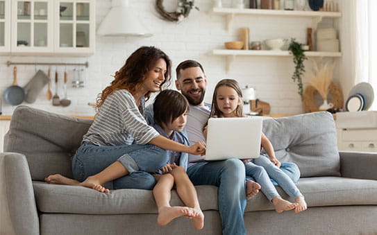 Family in their living room looking at a laptop