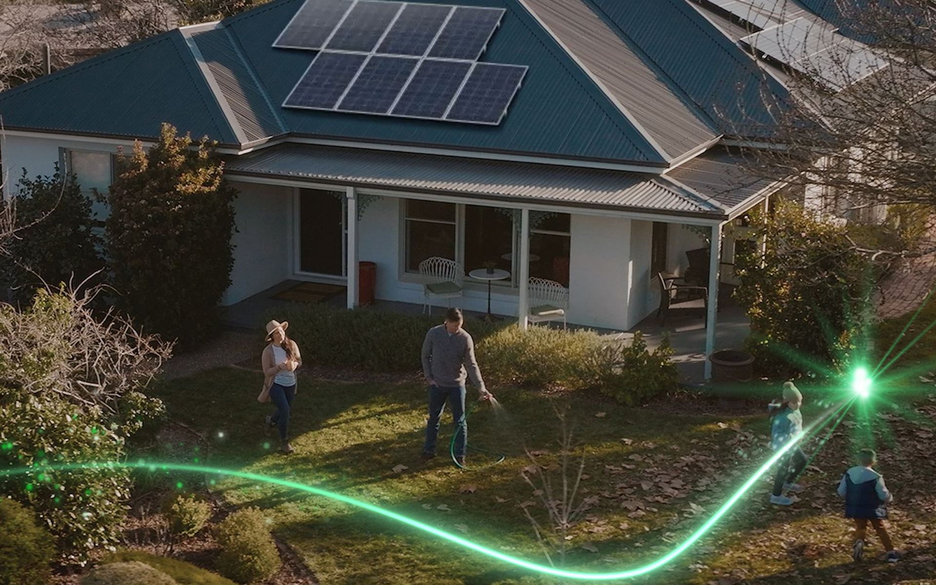 A couple outdoors by their home, watering the garden together